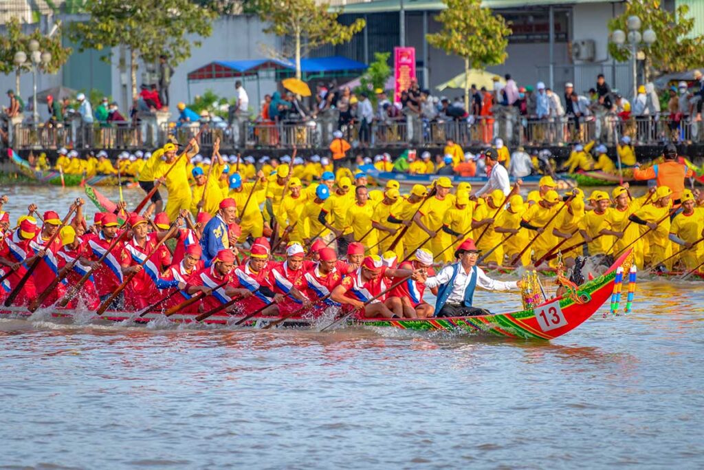 Two competing Khmer longboats in red and yellow racing side by side in the Ghe Ngo Boat Race Festival on the Maspero River, Soc Trang.