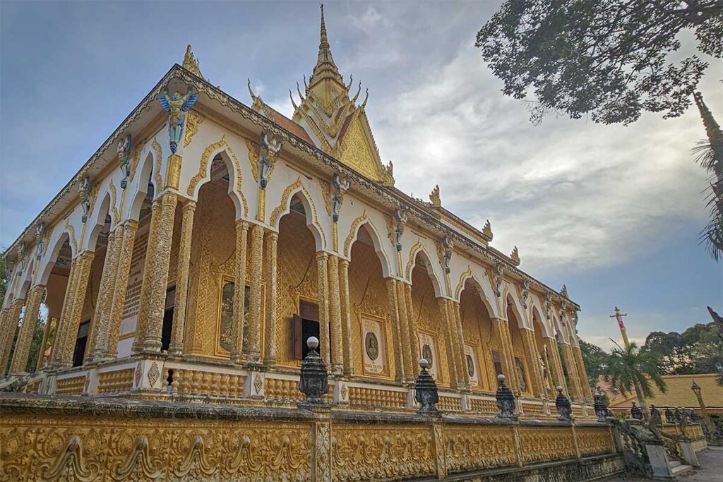 Side view of the richly decorated main hall of Nodol Pagoda in Tra Vinh with arched golden columns