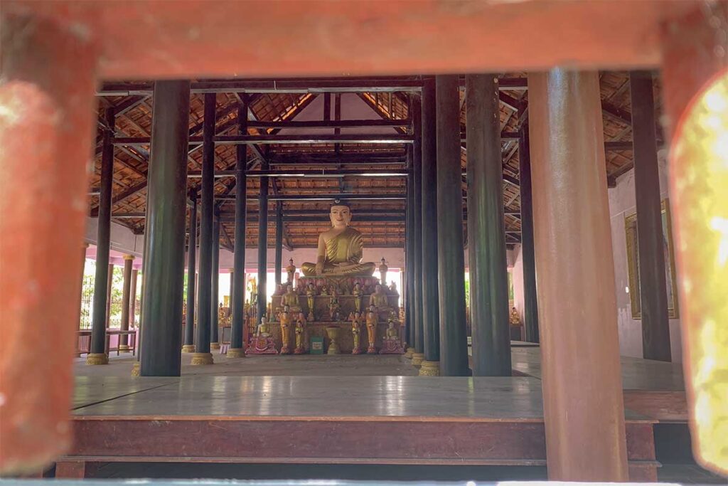 Interior of Nodol Pagoda main hall with a large seated Buddha statue and smaller surrounding statues