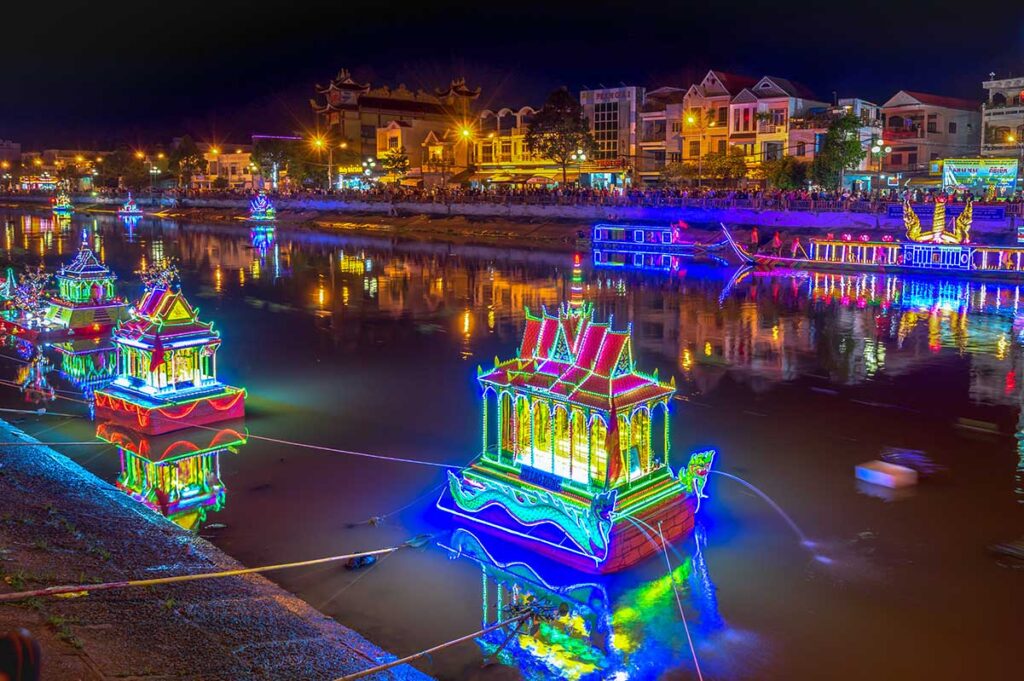 Colorful lantern floats on the Maspero River during Ok Om Bok Festival in Soc Trang, Vietnam, with crowds watching from the riverside.