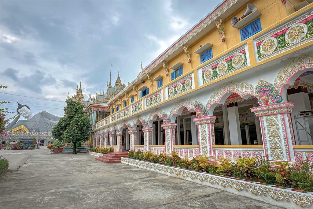The old Sala building at Som Rong Pagoda, now serving as a library, with pastel Khmer designs and the reclining Buddha visible in the background
