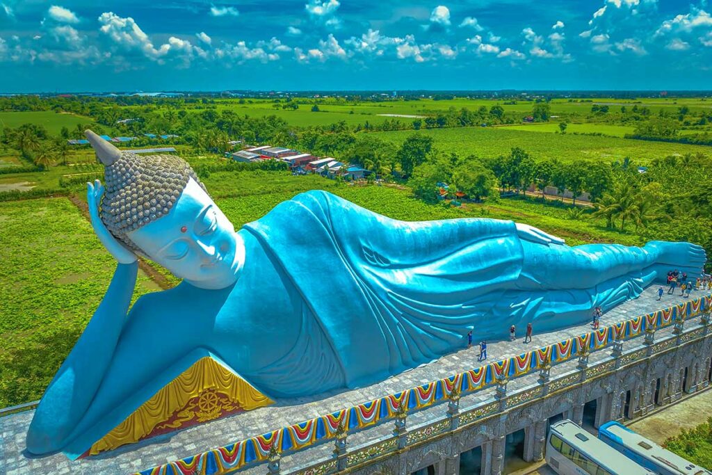 Closer aerial view of the reclining Buddha statue at Som Rong Pagoda, showing its serene face and raised platform with visitors walking along