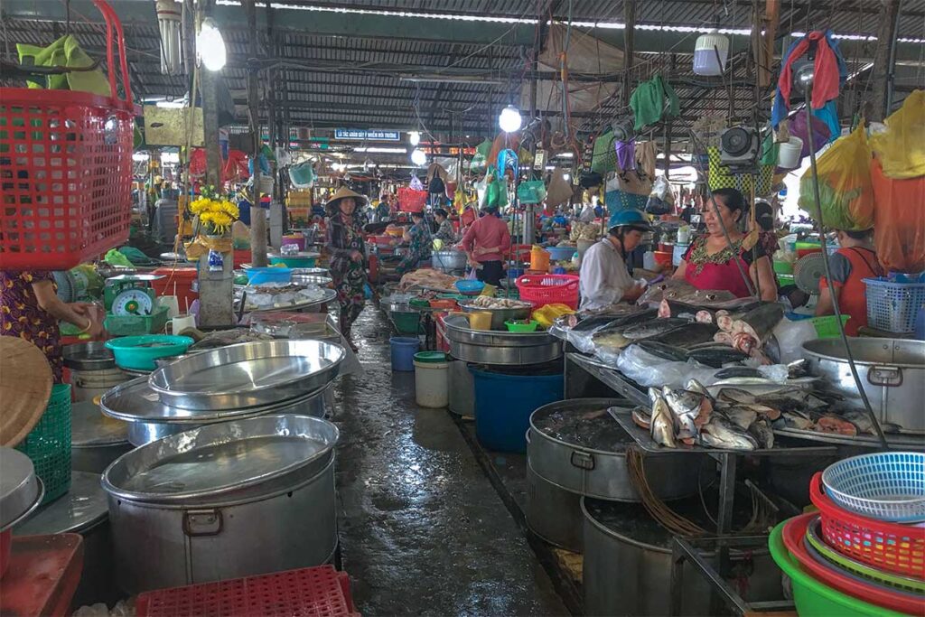 Indoor seafood section of Tân An Market in Cần Thơ with fresh fish displayed on ice and vendors in conical hats selling to locals.