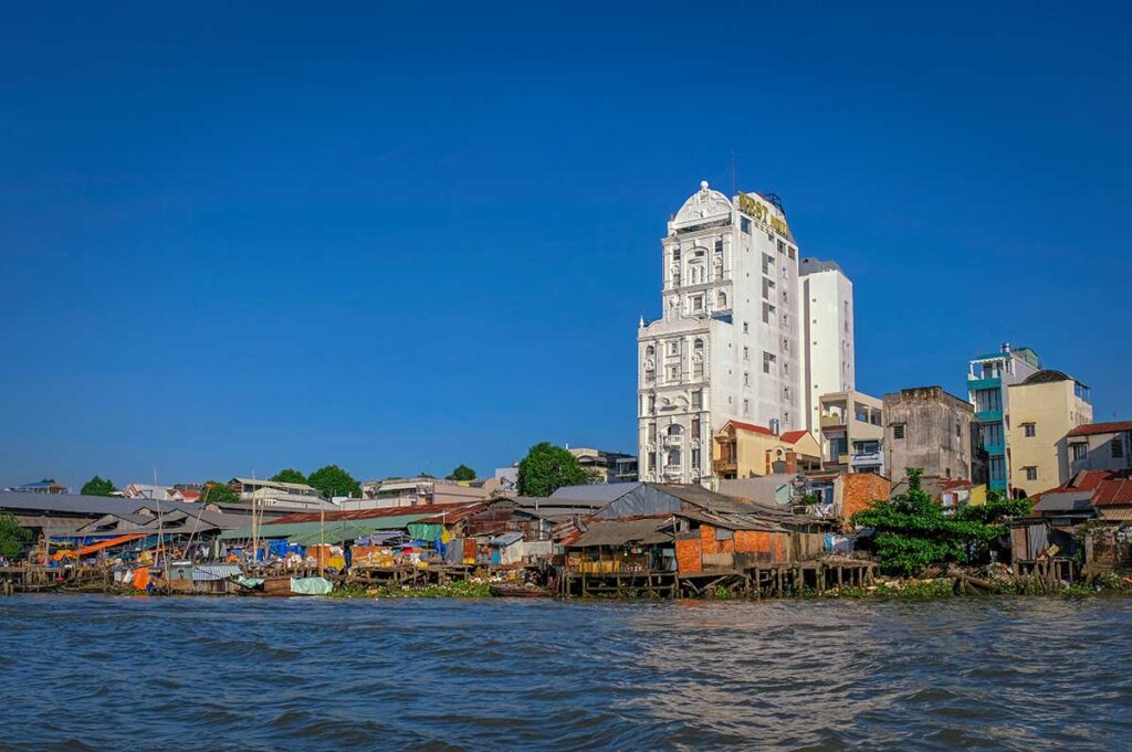 View of Tân An Market from the river in Cần Thơ with stilt houses and modern buildings in the background.