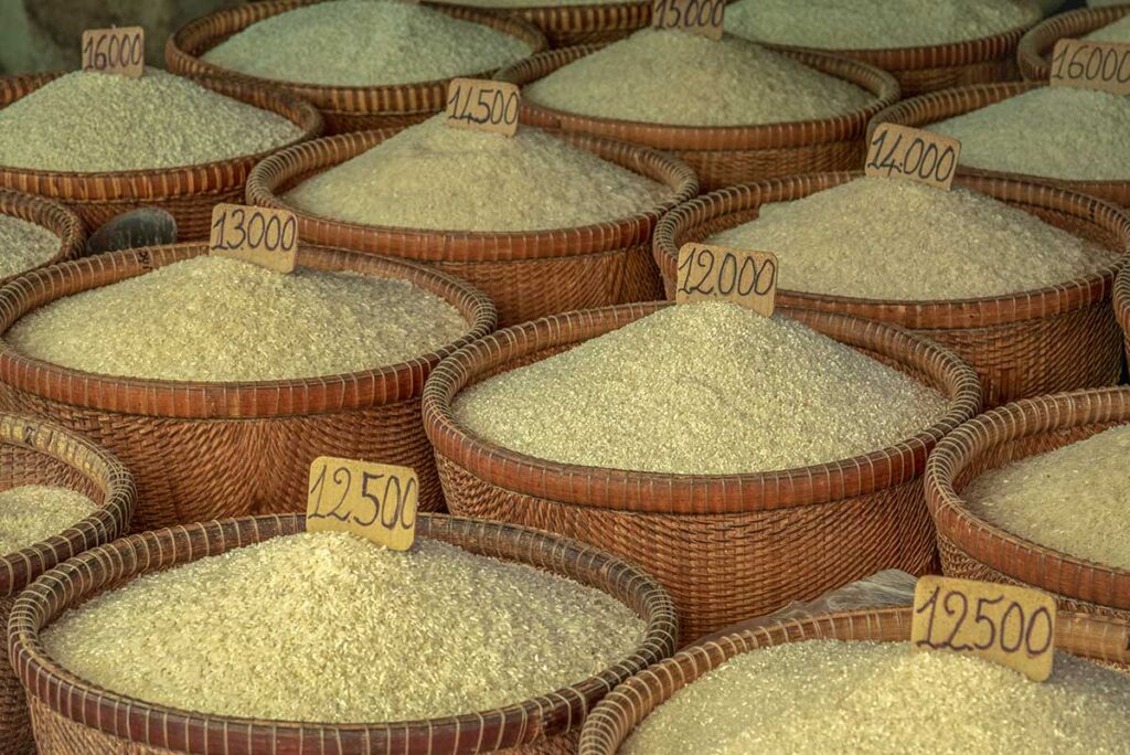 Baskets of rice varieties with price tags at Tân An Market in Cần Thơ, highlighting the region’s Mekong Delta produce.