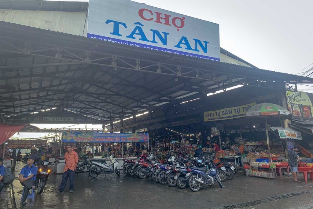 Entrance of Tân An Market in Cần Thơ with motorbikes parked outside and a large sign reading Chợ Tân An.