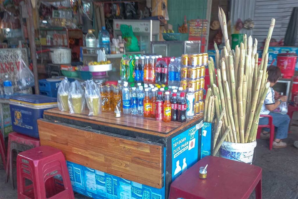 Beverage stall at Tan An Market Hoi An selling sugarcane juice, bottled soft drinks, and iced teas