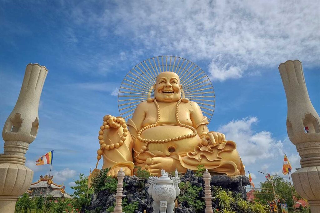 Golden Maitreya Buddha statue with dragon sculptures at Van Phuoc Pagoda, Ben Tre
