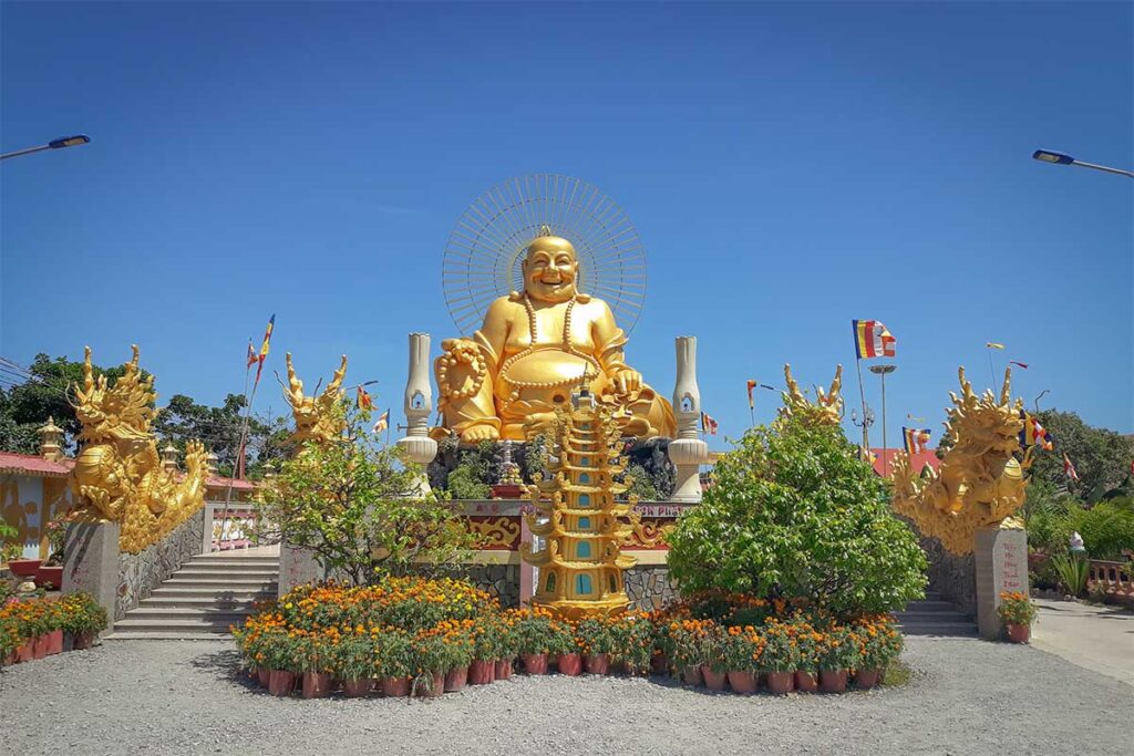 Golden Maitreya Buddha statue with dragon sculptures at Van Phuoc Pagoda, Ben Tre