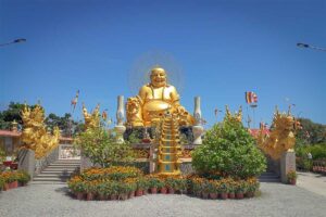 Golden Maitreya Buddha statue with dragon sculptures at Van Phuoc Pagoda, Ben Tre