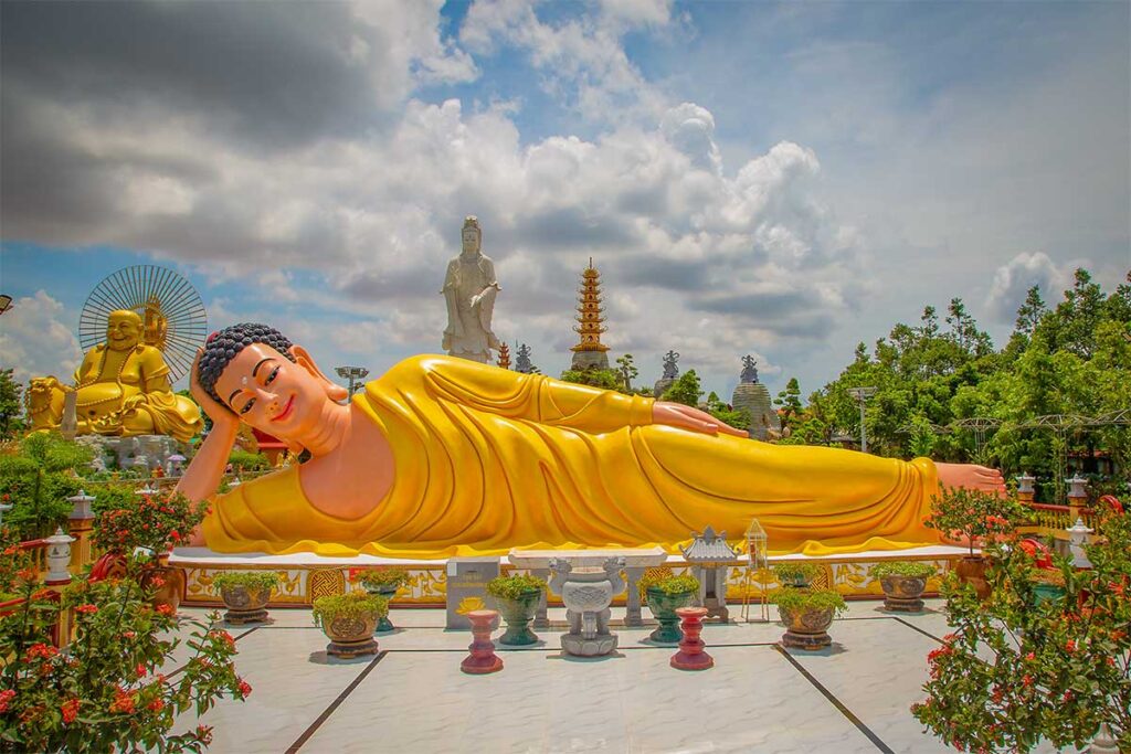 Reclining Buddha statue at Van Phuoc Pagoda in Ben Tre, with giant Maitreya and Avalokitesvara in the background