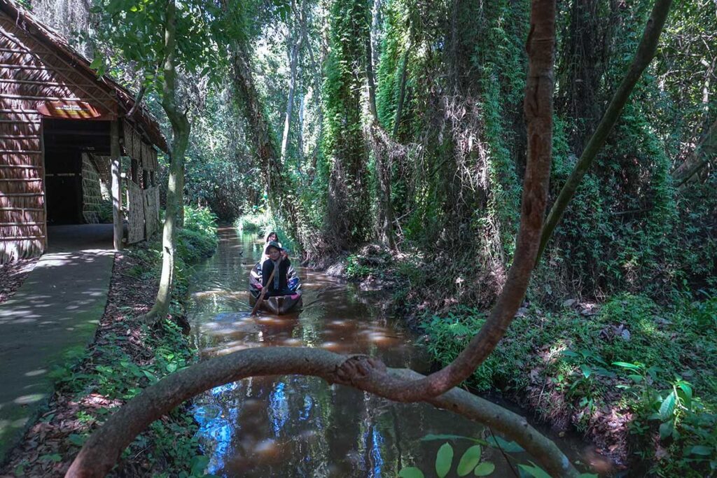 Sampan ride with tourists at Xeo Quyt Forest – Group enjoying a traditional rowboat through lush canals in Dong Thap.