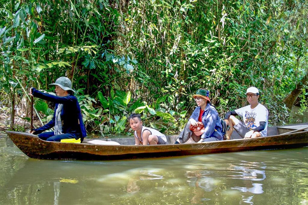 Sampan boat ride in Xeo Quyt Forest, Dong Thap – Tourists being rowed through shaded waterways surrounded by dense tropical greenery.