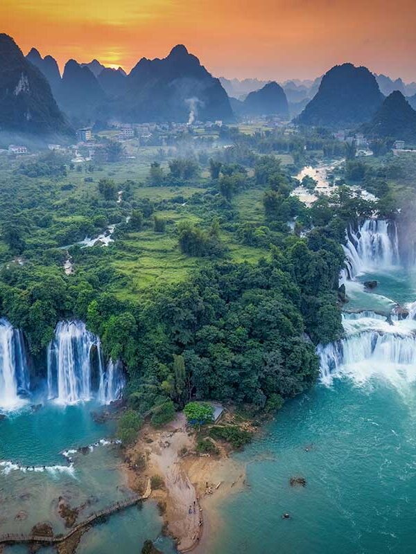 Cao Bang tours – Local Vietnam | aerial view of Ban Gioc Waterfall surrounded by limestone mountains at sunset