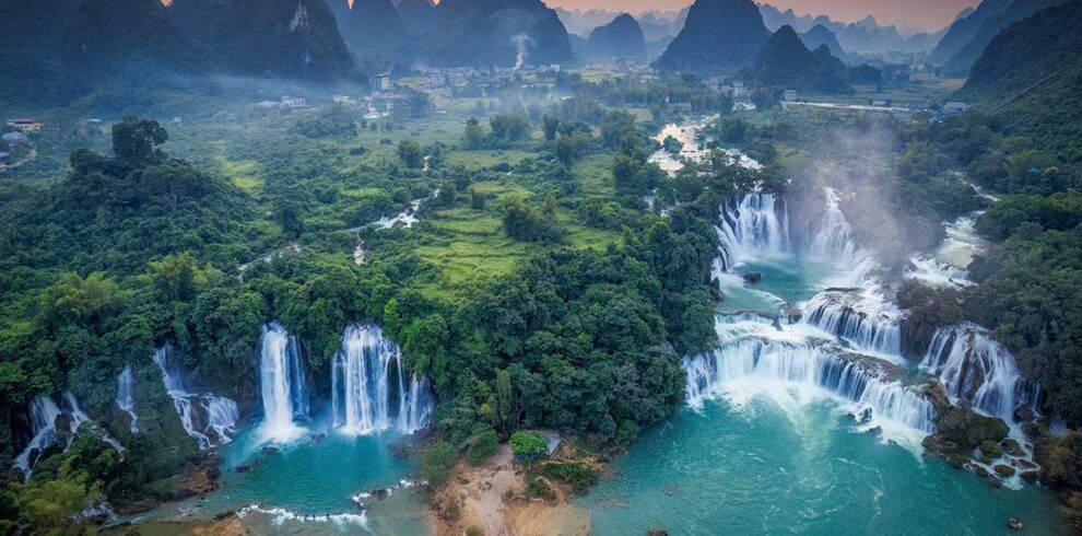 Cao Bang tours – Local Vietnam | aerial view of Ban Gioc Waterfall surrounded by limestone mountains at sunset
