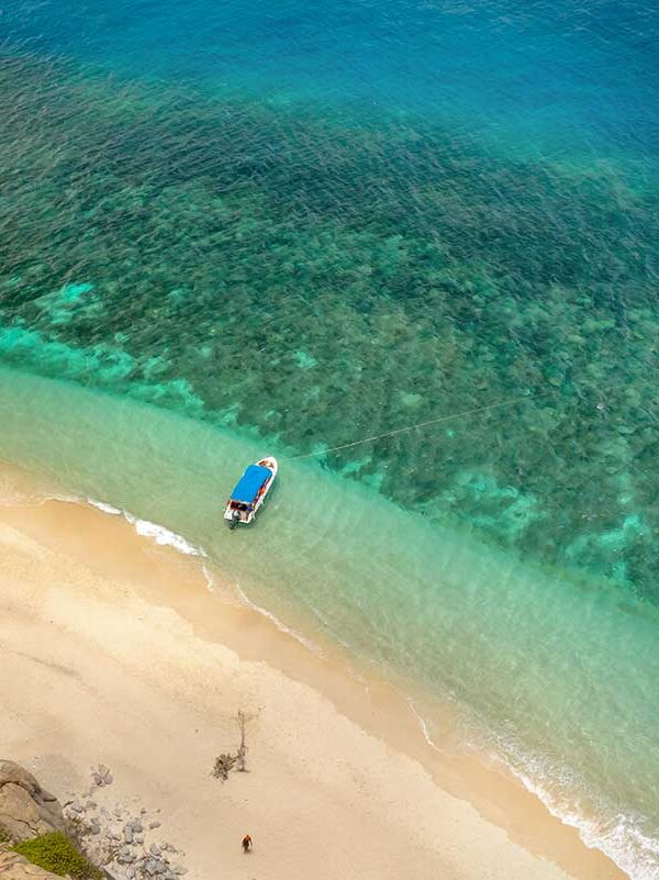 Con Dao tours – Local Vietnam | pristine beach and turquoise sea with local boat along Con Dao Island