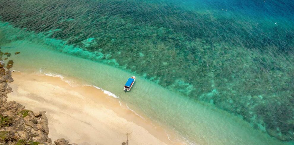 Con Dao tours – Local Vietnam | pristine beach and turquoise sea with local boat along Con Dao Island