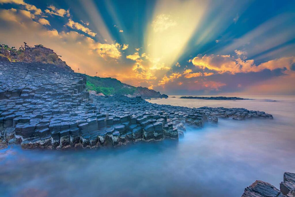Sunrise over Da Dia Reef in Phu Yen, Vietnam, with hexagonal basalt columns meeting the sea at the Sea Cliff of Stone Plates.