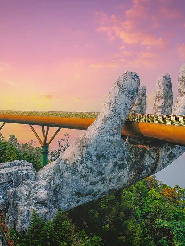 Golden Bridge Da Nang – Local Vietnam tours | aerial view of Ba Na Hills bridge held by giant stone hands at sunset