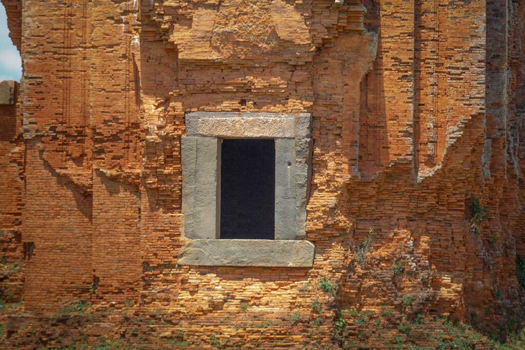 Detail of a sandstone-framed doorway at Duong Long Towers, set within the brick walls of the central sanctuary.