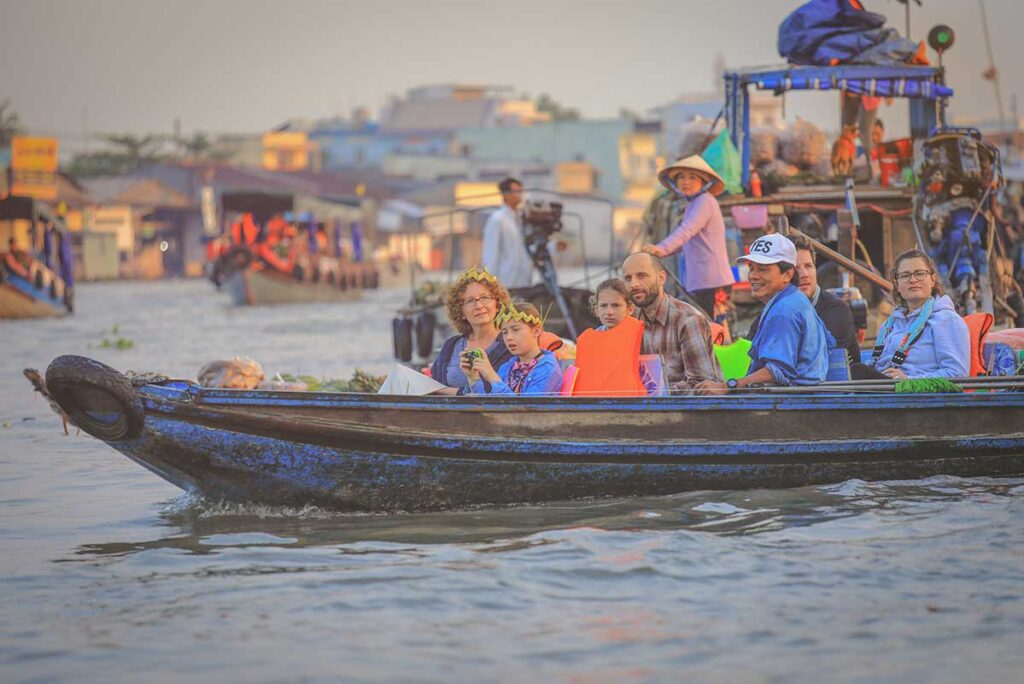 Family with kids on a boat visiting a floating market in the Mekong Delta, one of the most iconic and family-friendly experiences in the region.