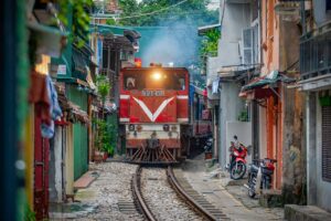 Hanoi tours – Local Vietnam | train passing through the narrow Hanoi Train Street surrounded by houses and cafés in the Old Quarter