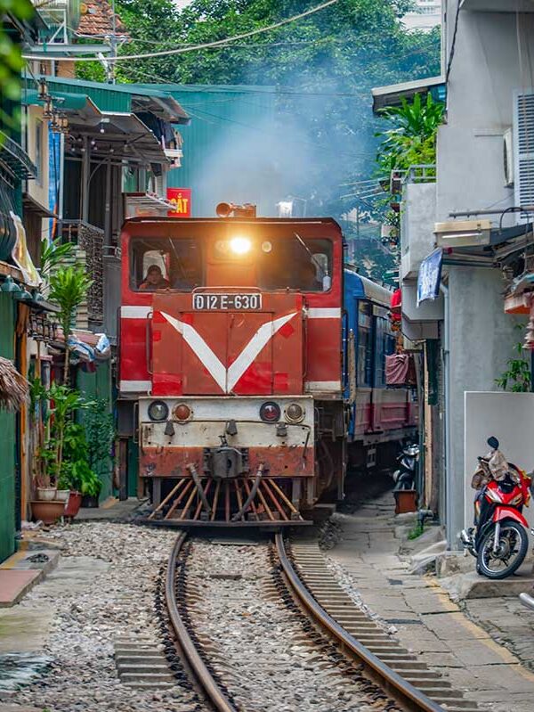 Hanoi tours – Local Vietnam | train passing through the narrow Hanoi Train Street surrounded by houses and cafés in the Old Quarter