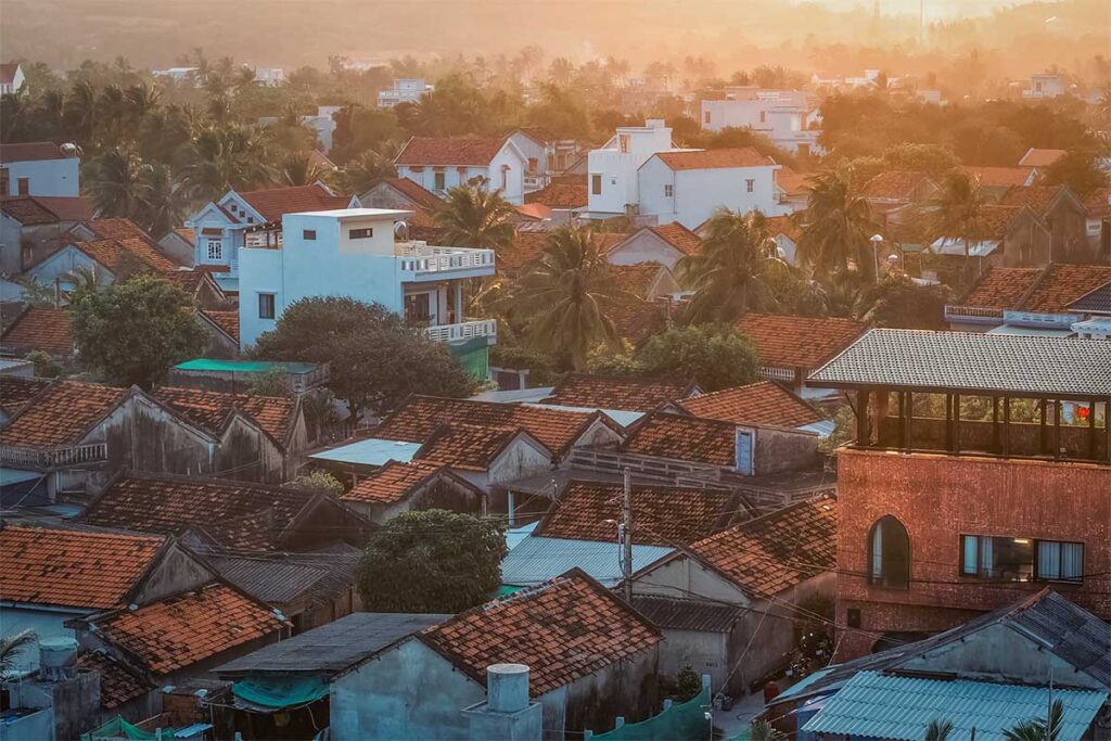 Long Thuy fishing village rooftops at sunset – Aerial view of the fishing village in An Phu Commune, near Tuy Hoa, with red-tiled roofs and palm trees glowing in the evening light.