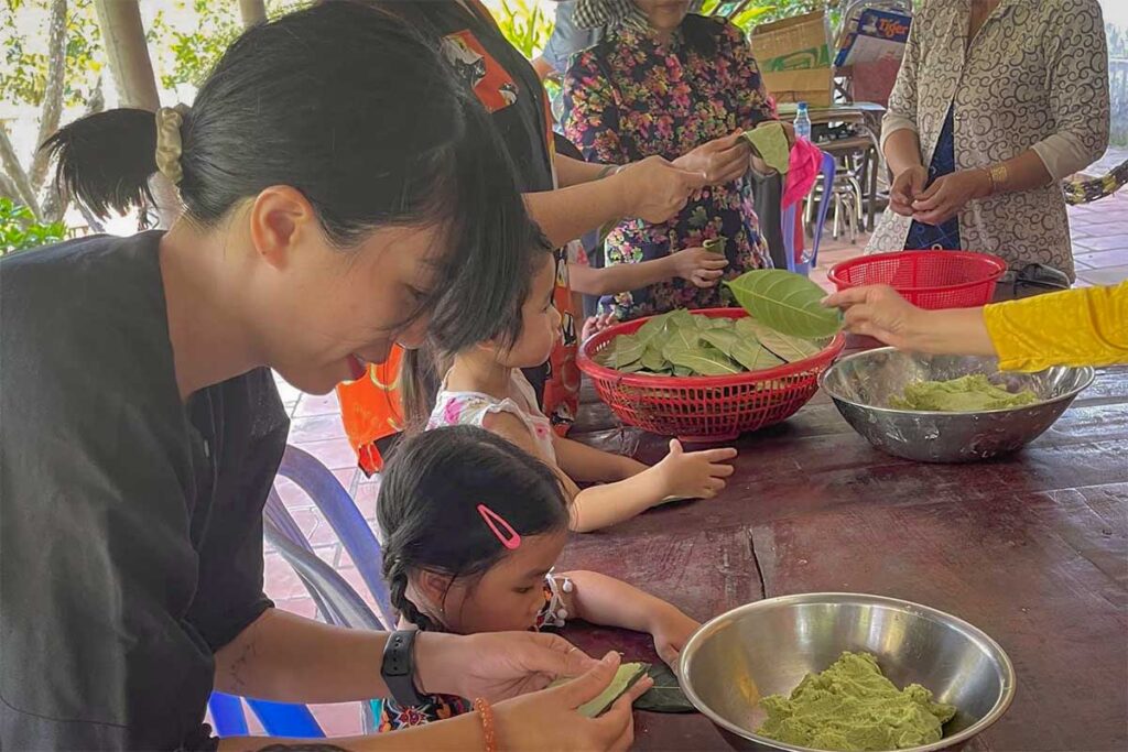 Children learning traditional skills at a local workshop in the Mekong Delta, using leaves and dough in a hands-on cultural activity.