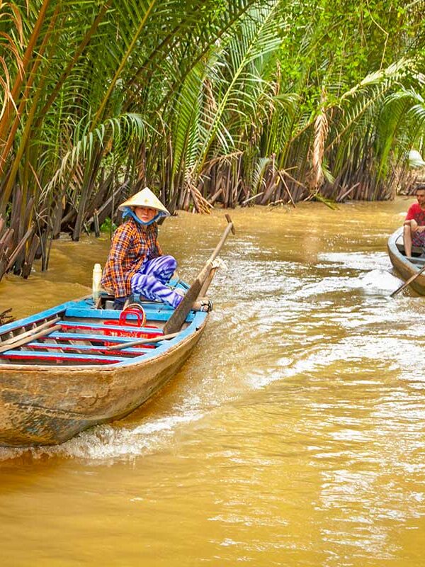 Mekong Delta Vietnam – Local Vietnam tours | local boat rowers navigating narrow palm canals with visitors on a Mekong Delta day trip