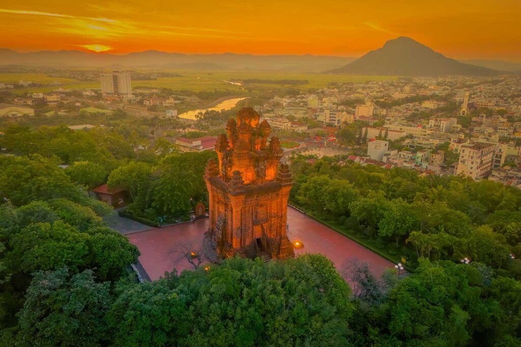 Nhan Tower at sunset illuminated above Tuy Hoa with Da Rang River and mountains in the distance