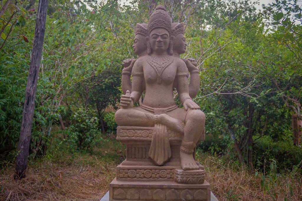 Stone statue of Lord Brahma along mountain path leading to Nhan Tower