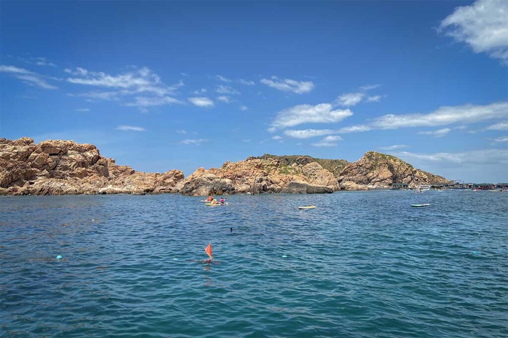 Kayaking near Hon Kho Island – Clear blue water and rocky cliffs make a scenic backdrop for visitors paddling kayaks just off the coast from Nhon Hai.