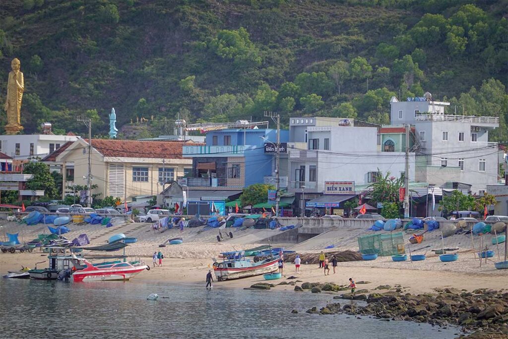 Waterfront of Nhon Ly village: homestays, seafood eateries and working boats pulled onto the sandy shore, Quy Nhon.