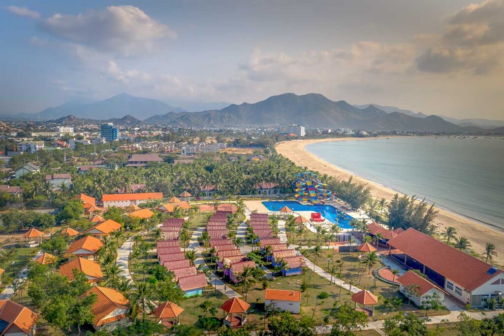 Golden sands and calm shoreline of Ninh Chu Beach, Phan Rang, lined with palm trees and sun umbrellas