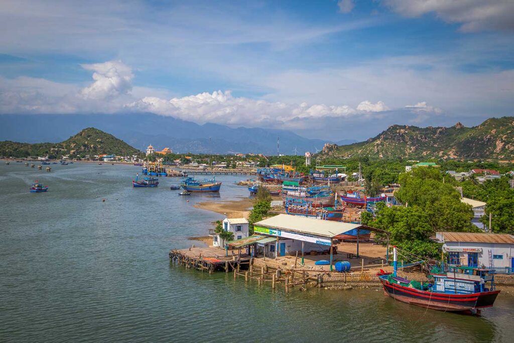 Colorful fishing boats moored at Ninh Chu fishing village, with views of Phan Rang’s coastal hills and mountains