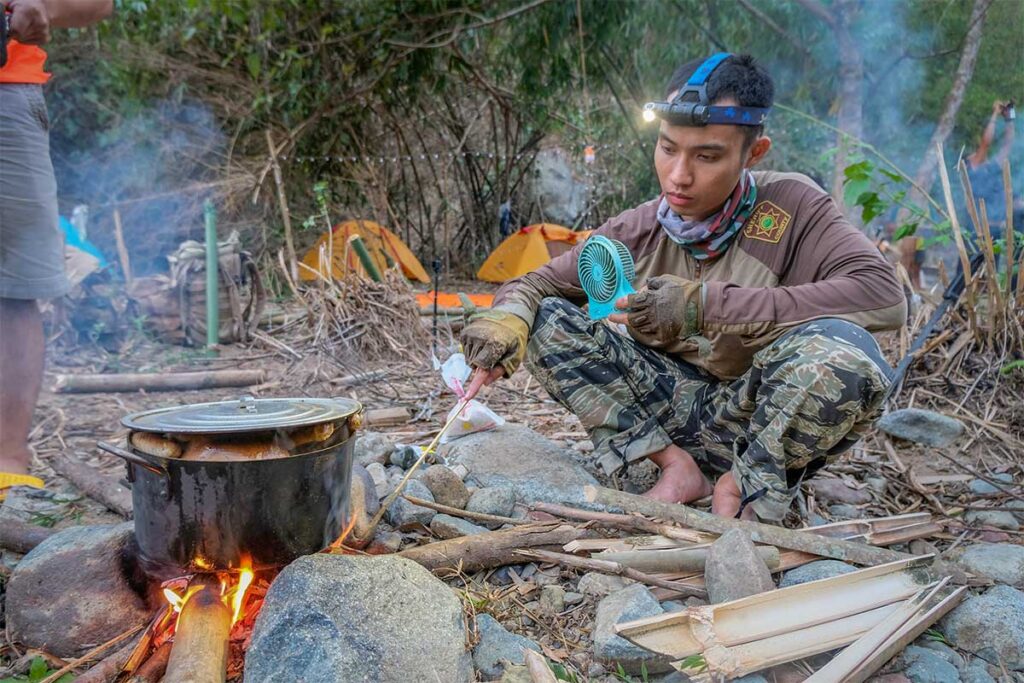 Campfire cooking in Phuoc Binh – Local guide preparing food over a campfire with bamboo and a cooking pot during a trekking trip.