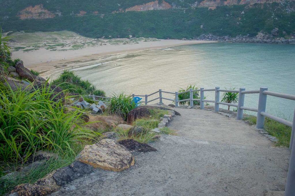 Pathway with railings descending towards Bai Mon Beach and turquoise water in Phu Yen, Vietnam.
