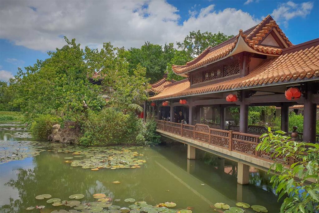 Lotus pond with traditional wooden bridge and tiled-roof pavilion at Thien Hung Pagoda in Binh Dinh.