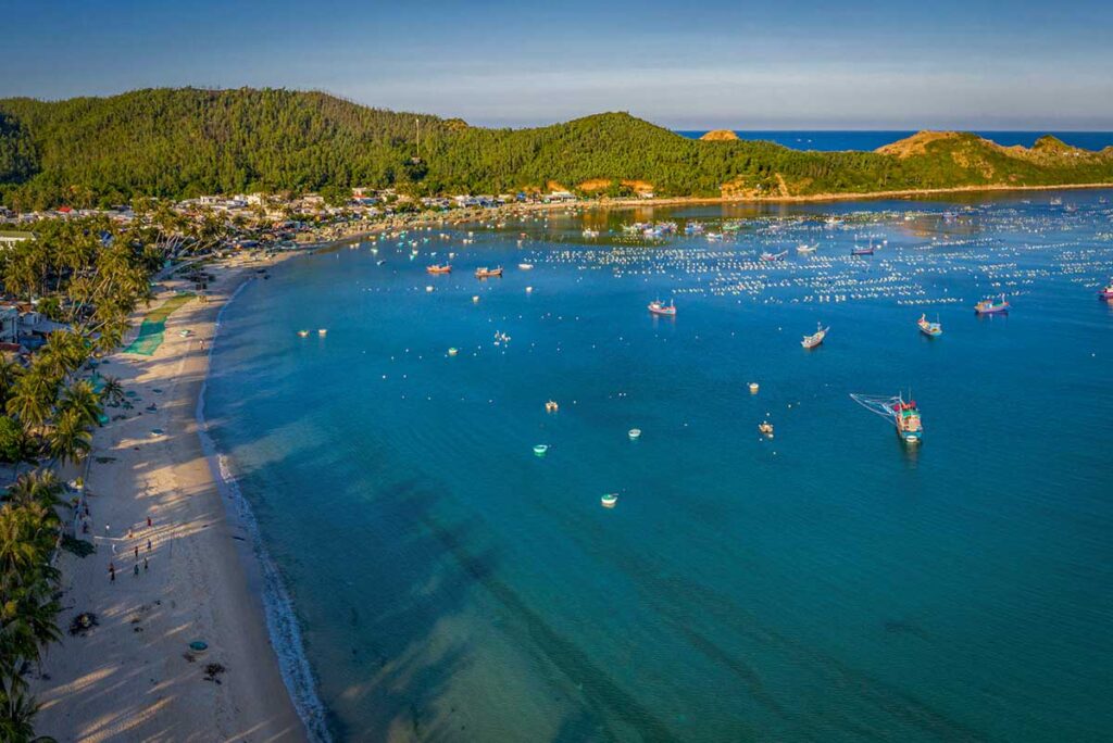Daily life at Vinh Hoa Fishing Village on Tu Nham Bay, with colorful round fishing boats and nets along the beach.