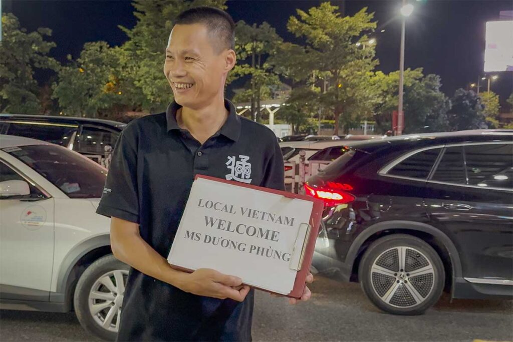 Local Vietnam driver waiting for airport pickup with welcome sign — professional car hire Vietnam service with reliable, English-friendly drivers and upfront pricing.