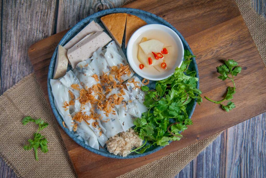 Banh cuon, Vietnamese steamed rice rolls served with fresh herbs, pork paste, fried shallots and a bowl of fish sauce dipping sauce