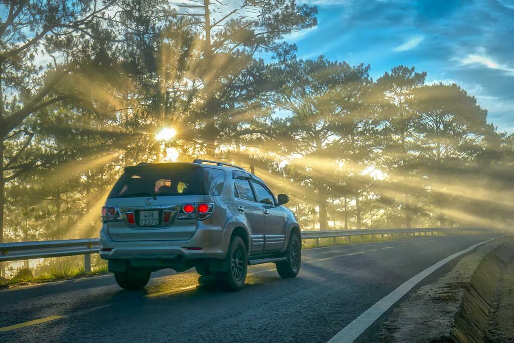 SUV driving through misty pine forest near Dalat at sunrise — an example of Vietnam car rental comfort and flexible day-trip travel.