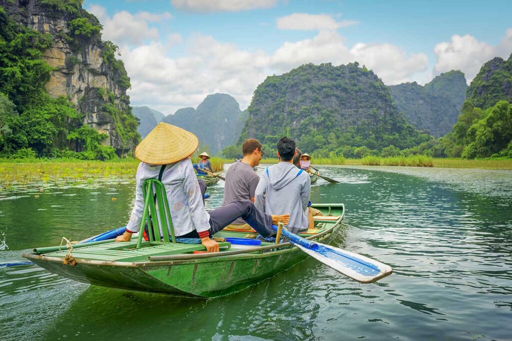Boat ride through limestone karsts and waterways in Ninh Binh, a scenic experience featured in most North Vietnam tours.