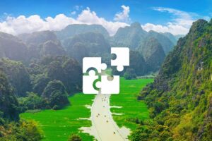 Private Ninh Binh tour with a custom itinerary, cruising through lush rice fields surrounded by tall limestone karst cliffs.