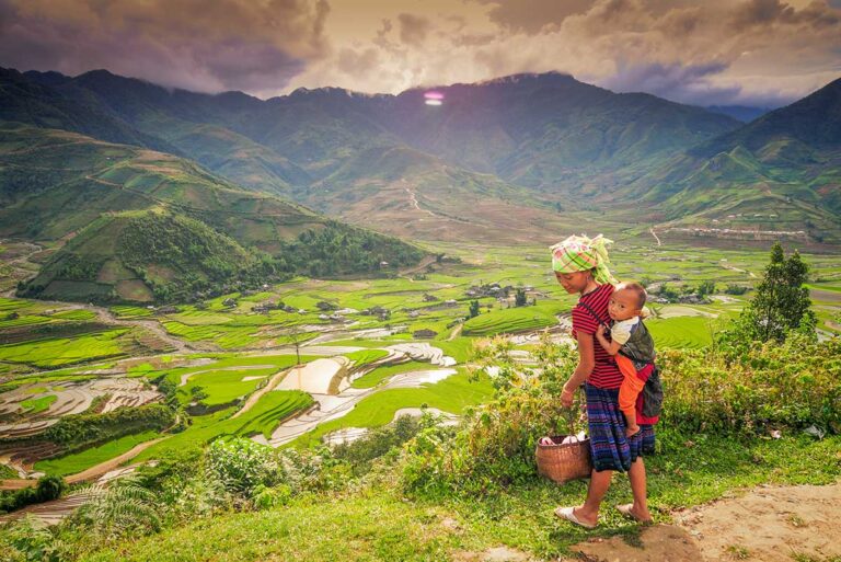 Hmong woman carrying her baby overlooking rice terraces in Sapa — a classic stop on cultural Vietnam tours and scenic Vietnam itineraries in the north.