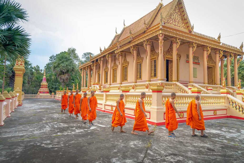 Soc Trang tours with Khmer monks walking past an ornate pagoda in southern Vietnam