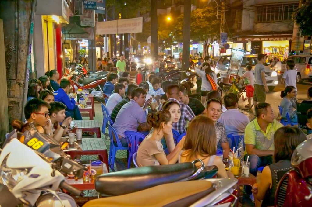Locals and travelers sitting at street cafés during a Ho Chi Minh City by night tour, experiencing the energy of South Vietnam.