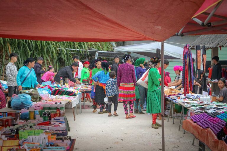 Colorful scene at Sung Trai Market in Ha Giang with ethnic minority vendors and traditional clothing.