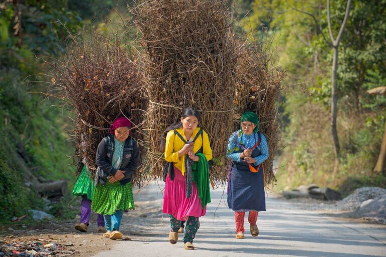 Ethnic women walking along a mountain road surrounded by limestone peaks on the Ha Giang Loop, a popular route for adventurous Vietnam tours.